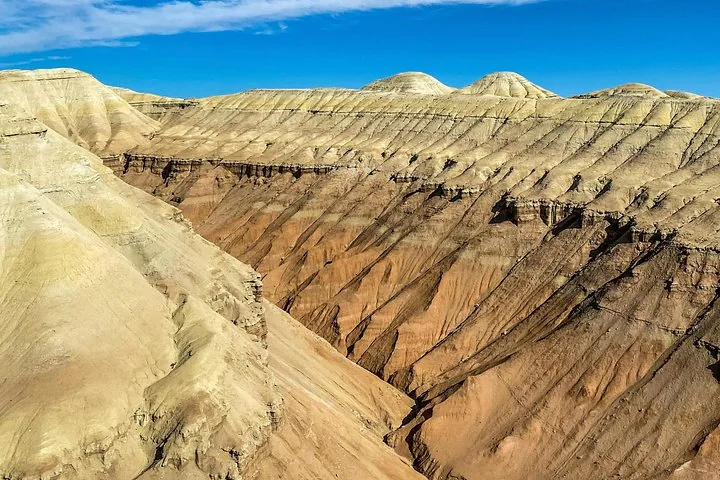Eine tiefe Schlucht, die durch die trockene, geschichtete Landschaft der Aktau-Berge führt.